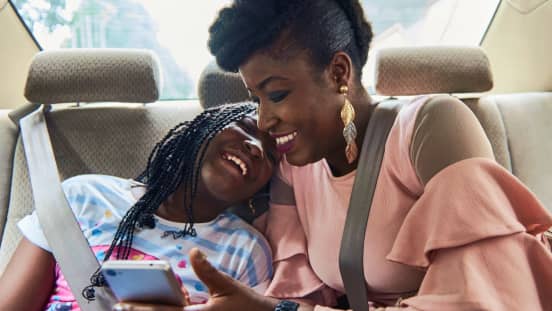 mulher e menina num automóvel uber com telemóvel 