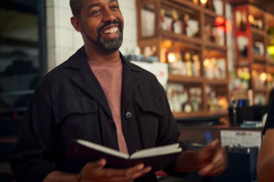 Black business owner holding a notebook and smiling