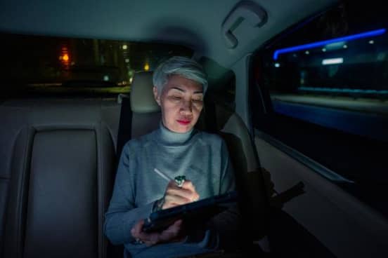 фотография женщины на заднем сидении автомобиля Uber, работающей на планшете