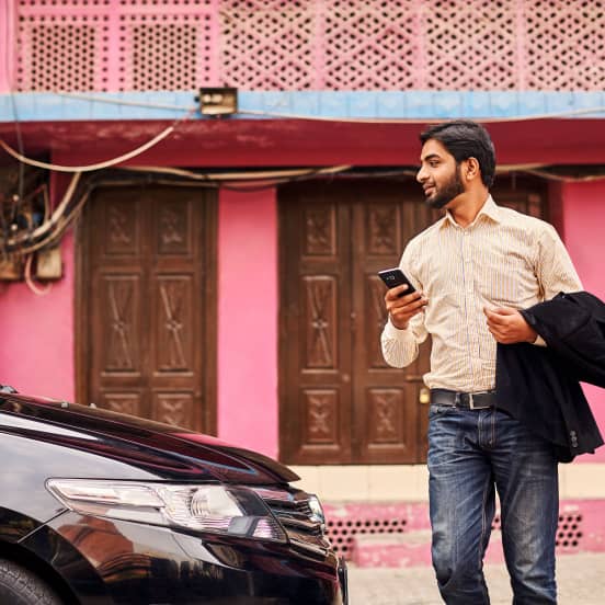 Man holding a phone getting into car