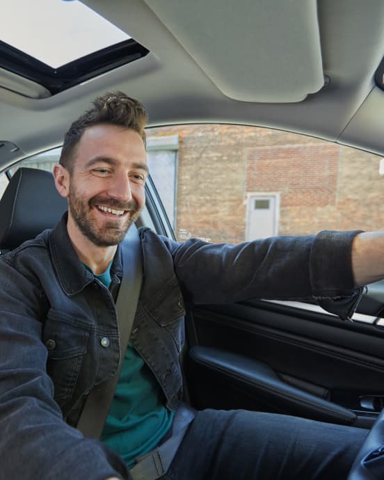 Photo of a driver-partner smiling while driving his car